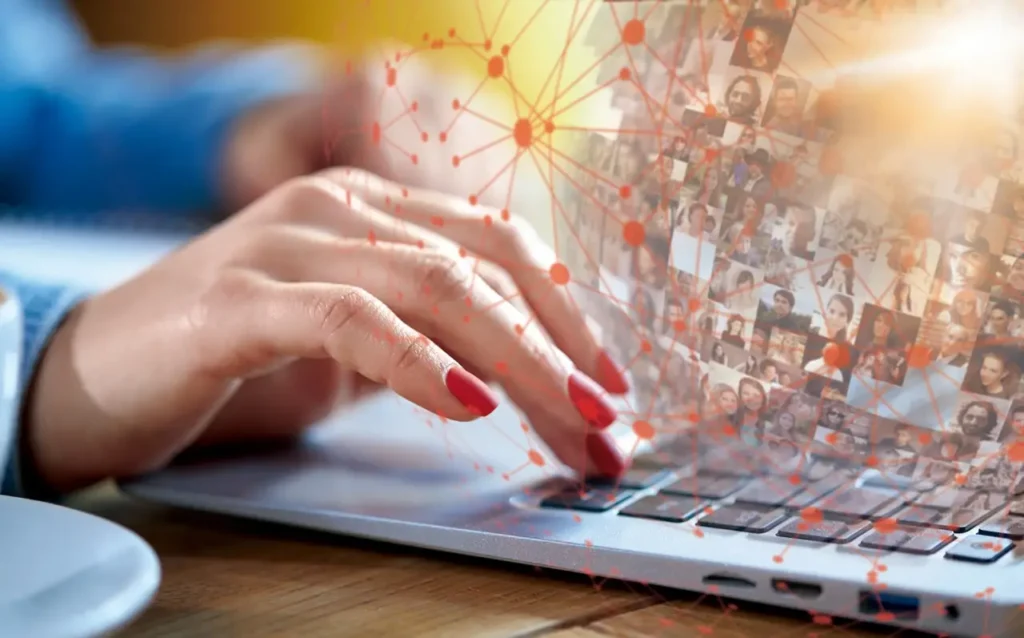 a hand over a laptop with an overlay of interconnected photos of people, signifying the modern hiring methods