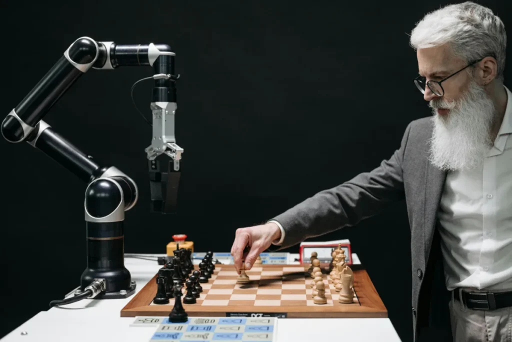 A robotic arm playing chess against a man with a white beard wearing a suit, symbolizing artificial intelligence and human interaction.