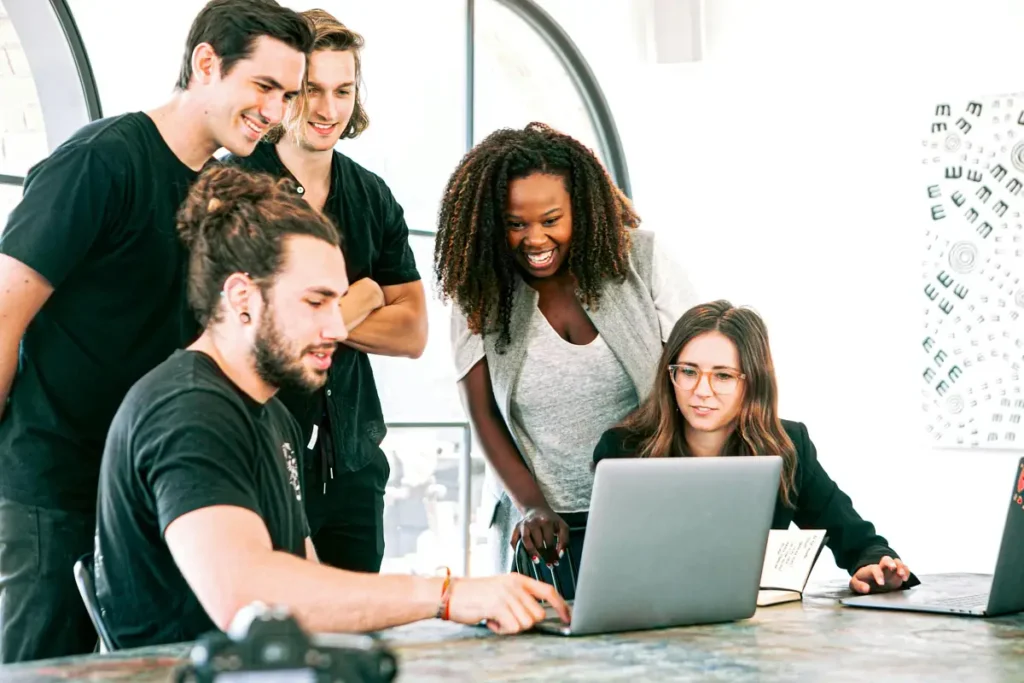 a group of people looking at a laptop, helping each other arrive at a decision