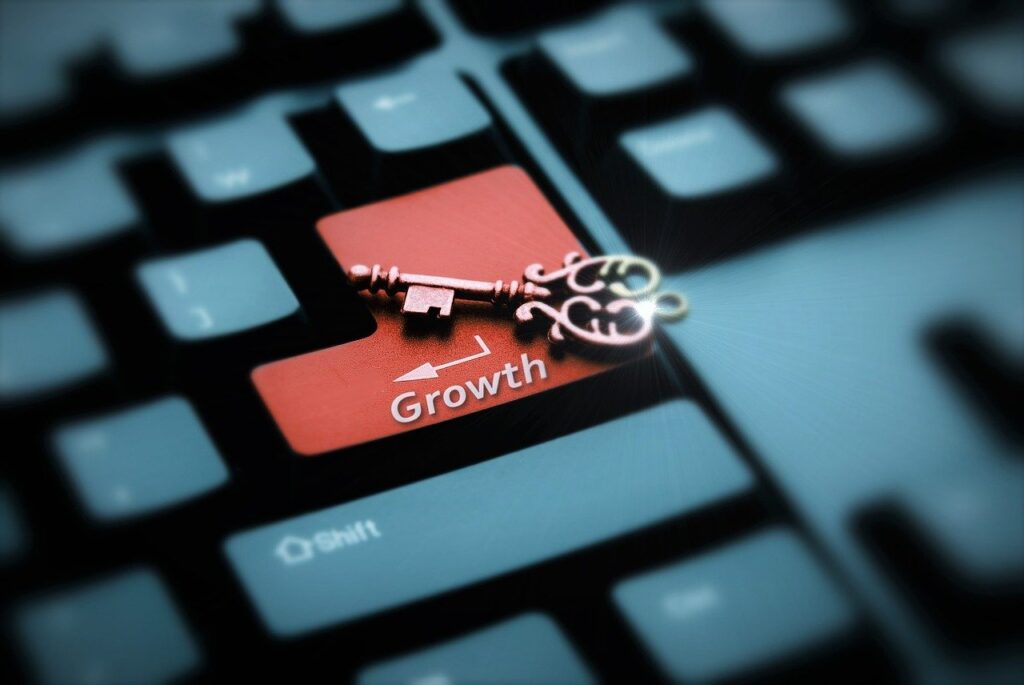 A close-up of a computer keyboard featuring a large red key labeled "Growth," with an ornate key placed on top, symbolizing unlocking business growth opportunities.
