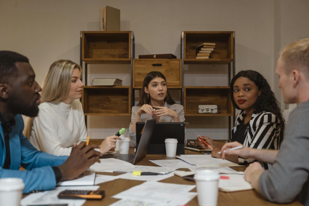 A meeting scene illustrating the greatest leadership strengths, where a diverse group of professionals listen and collaborate as one woman leads the discussion.